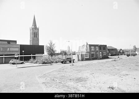 Zwei Häuser werden abgerissen. Whizgle News, Dutch Desk, Niederlande, 1950 - 2000. Das Bild enthält diese Themen. Die Szene präsentiert eine ruhige urbane Umgebung, die durch einen starken Kontrast zwischen älterer und neuerer Architektur gekennzeichnet ist. Auf der linken Seite steht ein modernes Gebäude mit flacher Fassade, stromlinienförmig und minimalistisch, das sich in die Kulisse eines klaren Himmels einfügt. Seine Oberfläche ist neutral und trägt zu einem Gefühl zeitgenössischer Einfachheit bei. Im Gegensatz dazu zeigt die rechte Seite eine Gruppe traditionellerer Gebäude. Ein Gebäude, das ein markantes rotes Backsteingebäude aufweist, ist besonders zu nennen Stockfoto