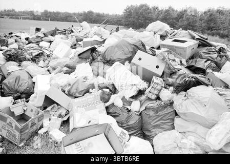 Hap of Garbage, Whizgle News, Dutch Desk, Niederlande, 1950 - 2000 im Jahr 1989. Dies sind die Elemente im Bild. Die Szene ist ein großer, unorganisierter Haufen von Abfallgegenständen, der ein chaotisches visuelles Spektakel erzeugt. Verschiedene Arten von Müll stapeln sich hoch, darunter zerknitterte Plastikbeutel, zerrissene Kartons und einige Metalldosen, was auf eine Mischung von Haushaltsabfällen hinweist. Die Farben sind überwiegend monochromatisch, da die Einstellung in Schwarzweiß erfolgt. Diese Wahl unterstreicht die Strenge des Mülls und die fehlende Lebendigkeit, was ein Gefühl von Vernachlässigung und Verfall hervorruft. Schatten spielen über den Hügel, Stockfoto
