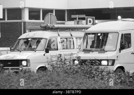 RLD Aktionen Schiphol Demonstration Schiphol, Whizgle News, Dutch Desk, Niederlande, 1950 - 2000 am 11-11-1983. Diese Themen werden in der Abbildung angezeigt. In der Szene stehen zwei Vintage-Vans dicht nebeneinander. Der erste Van auf der linken Seite ist ein älteres Modell, das sich durch seine Kastenform und einen markanten Frontgrill auszeichnet. Er hat eine helle Farbe, möglicherweise weiß oder Creme, mit einem dunklen Streifen entlang der Seite. Das Dach hat einen Leiterträger, was auf einen Zweckgebrauch hindeutet, vielleicht für ein Servicefahrzeug. Der zweite Van, etwas moderner, präsentiert sich mit seinem runden Erscheinungsbild in Kontrastfarbe Stockfoto