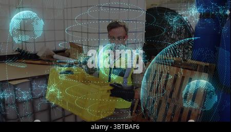 Tragen einer Sicherheitsweste, Arbeiter hält gelbe Kiste im Lager, mit Paletten und holografischer Überlagerung Stockfoto