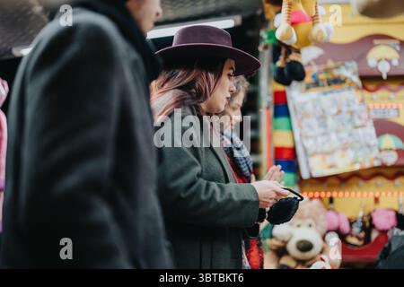Frau mit Hut erkundet den pulsierenden Wintermarkt mit Freunden Stockfoto