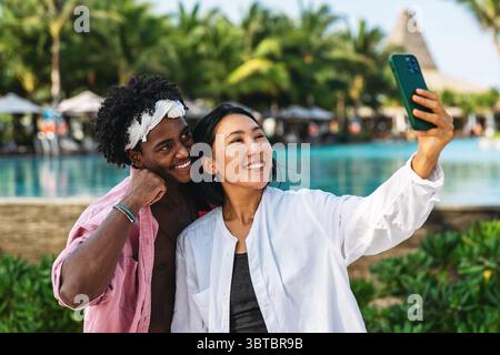 Vielfältige Paare verbunden, mit Technologie und sozialen Medien, während Sie Momente am Strand genießen Stockfoto