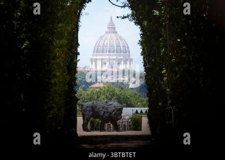 14. Juli 2025, Rom, Italien: Die Kuppel des Petersdoms bildet die Kulisse für den bronzenen Löwen zu Ehren von Papst Leo XIV. In den Gärten der Magistralvilla des Souveränen Malteserordens auf der Piazza dei Cavalieri di Malta auf dem Aventinenhügel in Rom wurde Eine Bronzeskulptur eines Löwen von Davide Rivalta in den Gärten der Magistralvilla des Souveränen Malteserordens aufgestellt. sichtbar durch das Schlüsselloch der Piazza dei Cavalieri di Malta, dank der Zusammenarbeit mit der National Gallery of Modern and Contemporary Art in Rom. der souveräne Militärgastgeber Stockfoto