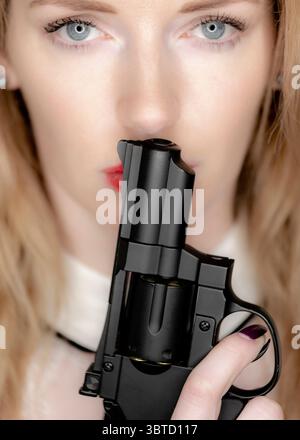 Eine Frau hält einen Revolver an den Mund. Stockfoto