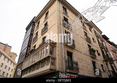 Besucher bewundern das einzigartige Design eines historischen Gebäudes in Pamplona, Navarra, umgeben von Feiertagsdekorationen, die den Geist des Feierns verkörpern Stockfoto