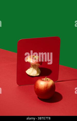 Apfel, der in den Spiegel blickt, sieht den gegessen Kern anstelle von ganzen Früchten Stockfoto