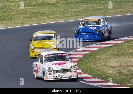 Drei Trabant 601-Fahrzeuge, die im historischen Motorsport auf dem Most Circuit (Tschechische Republik) antreten. Ein weißer, ein gelber und ein blauer Trabant rasen durch Stockfoto