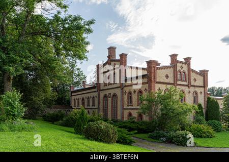 Rückansicht der Mooste Distillery, ein historisches Gebäude aus rotem Backstein und Stein, umgeben von Grün in Estland Stockfoto