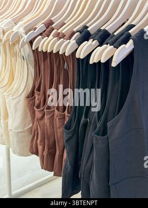 Tank Top Trio auf Holzbügeln. Beige, Braun und Schwarz Stockfoto