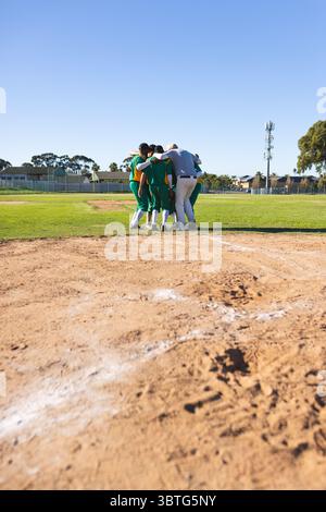 Verschiedene männliche Baseballteams drängen sich auf Pitcher Mound und tragen grüne und gelbe Trikots Stockfoto