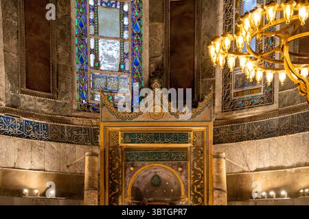 Der kunstvoll verzierte Mihrab wird von großen Kandelabern eingerahmt und unter Buntglasfenstern in der Hagia Sophia Grand Moschee in Istanbul, Türkei, platziert. Stockfoto