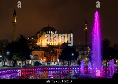 Hagia Sophia Moschee und der Sultanahmet Brunnen beleuchtet bei Nacht mit leuchtenden violetten Lichtern vor dem dunklen Istanbul Himmel. Stockfoto