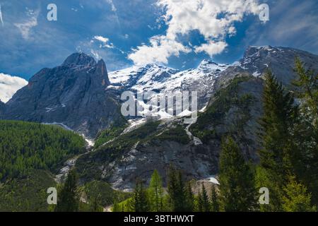 Die imposanten schneebedeckten Gipfel der Marmolada, Königin der Dolomiten, stehen majestätisch vor einem leuchtend blauen Himmel mit verstreuten Wolken. Stockfoto