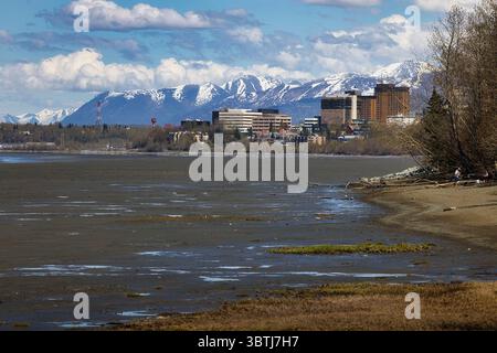 Anchorage, Alaska - 15. Mai 2024: Gebäude in Anchorage, Alaska am Wasser mit Bergen im Hintergrund an einem sonnigen Frühlingstag. Stockfoto