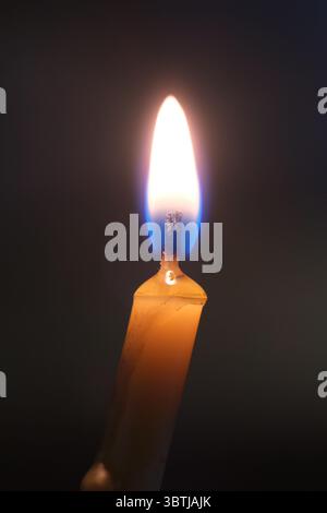 Die runde Paraffinkerze brennt auf schwarzem Hintergrund. Nahaufnahme sogar lange Flammen Stockfoto