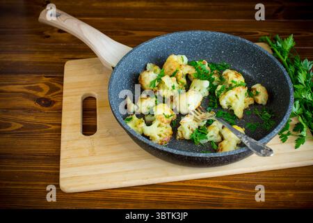 Appetitlicher gebratener Blumenkohl auf dunkler Küchenoberfläche. Stockfoto