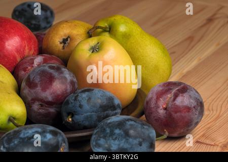 Süße reife Birnen, Äpfel und Pflaumen auf einem hellen Holztisch aus nächster Nähe Stockfoto
