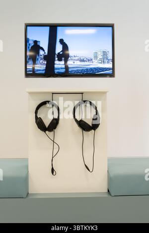 Der Aufnahmeraum. Kopfhörer hängen an der Wand. Der Fernseher ist an der Wand. An der Wand hängen moderne Kopfhörer Stockfoto