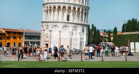 Pisa, Italien - 26. Juni 2025: Touristen versammeln sich an einem sonnigen Tag nahe dem Fuß des Schiefen Turms von Pisa, machen Fotos und genießen das berühmte Wahrzeichen Stockfoto