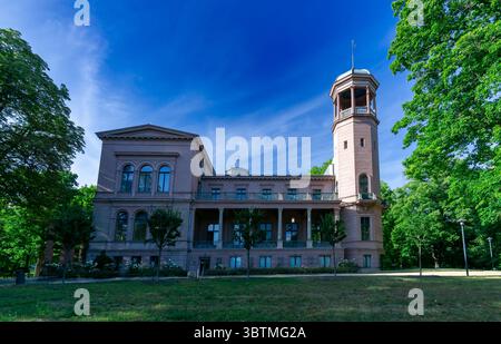 Schloss Biesdorf in Berlin an einem hellen Sommertag, umgeben von grünen Bäumen und blauem Himmel, vom Vorgarten aus gesehen. Stockfoto