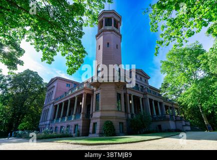 Schloss Biesdorf mit seinem berühmten Turm und Garten in Berlin an einem hellen Sommertag, umgeben von grünen Bäumen und klarem blauen Himmel. Stockfoto