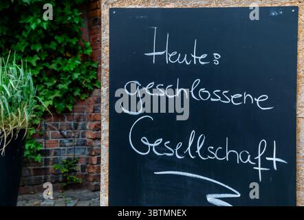 Handgeschriebenes Kreidezeichen auf Deutsch, das eine private Veranstaltung ankündigt. Stockfoto
