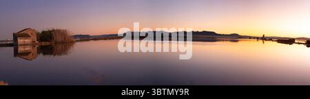Panoramablick auf Valencias Albufera-Reisfelder, die im Abendglühen untergetaucht sind, mit Wasserreflexionen und traditionellen Häusern in ruhiger Umgebung Stockfoto