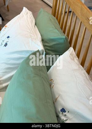 Holzlattenbett mit grünen und bestickten weißen Kissen. Gemütlicher Kontrast in Texturen Stockfoto