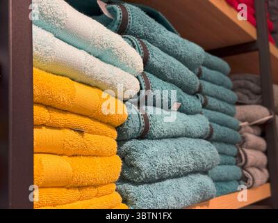 Mehrfarbige Handtücher auf industriellen Holzregalen, Pastell und Bold Textile Harmony Stockfoto