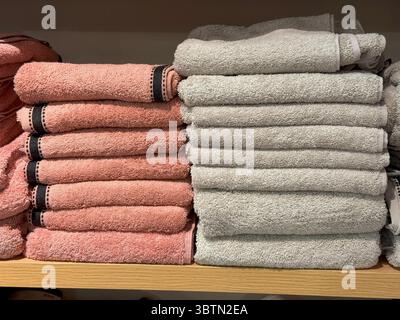 Mehrfarbige Handtücher auf industriellen Holzregalen, Pastell und Bold Textile Harmony Stockfoto