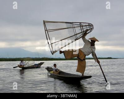 Intha-Fischer navigieren geschickt durch den Inle-See mit ihrer einzigartigen Beinrudertechnik, eine jahrhundertealte Tradition, die verkörpert Stockfoto