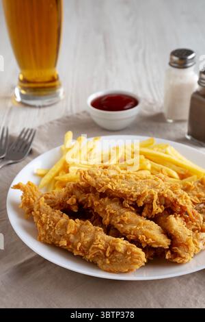 Hausgemachte Hähnchenstreifen mit Pommes frites auf einem Teller, Blick aus einem niedrigen Winkel. Nahaufnahme. Stockfoto