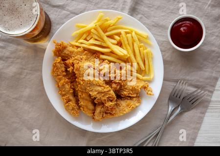 Hausgemachte Hähnchenstreifen mit Pommes frites auf einem Teller, Draufsicht. Stockfoto