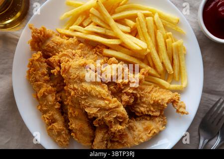 Hausgemachte Hähnchenstreifen mit Pommes frites auf einem Teller, Draufsicht. Stockfoto