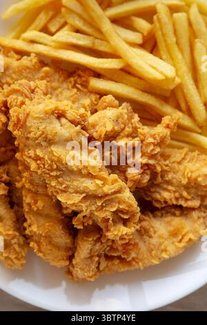 Hausgemachte Hähnchenstreifen mit Pommes frites auf einem Teller, Draufsicht. Nahaufnahme. Stockfoto