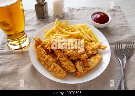Hausgemachte Hähnchenstreifen mit Pommes frites auf einem Teller, Seitenansicht. Stockfoto