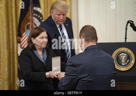 7. November 2019, Washington, DC, Vereinigte Staaten von Amerika: Susan Rescorla, Ehefrau der Presidential Citizens Medal posthum Empfänger Richard C. Rescorla überreicht die Medaille ihrem Sohn Trevor, während Präsident Donald Trump während der Zeremonie im East Room des Weißen Hauses am 7. November 2019 in Washington, DC, zusieht. Rescorla half, das Leben von fast 2.700 Menschen im World Trade Center am Morgen des 11. September 2001 zu retten. (Kreditbild: © Tia Dufour via ZUMA Wire) Stockfoto