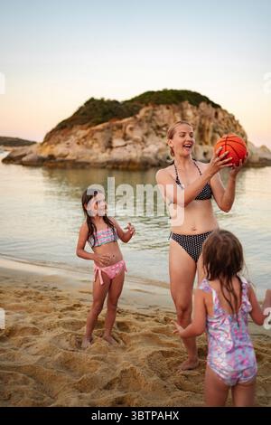 Die fröhliche Familie genießt einen sonnigen Tag beim Basketball am Strand Stockfoto