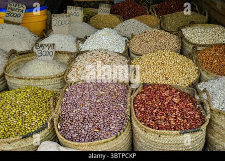 Verschiedene Arten von Bohnen, Getreide und Reis werden in gewebten Körben auf einem lokalen Markt präsentiert. Stockfoto