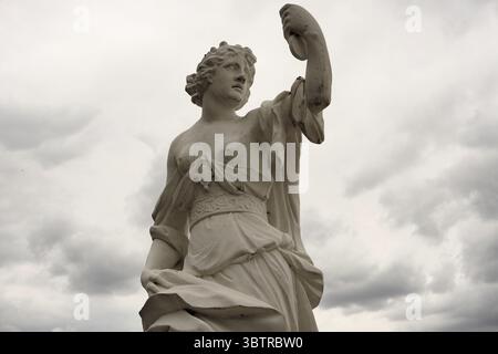 Eine wunderschöne Marmorstatue von Melpomene, der antiken griechischen Muse der Tragödie, hält eine tragische Maske vor einem dramatischen bewölkten Himmel Stockfoto