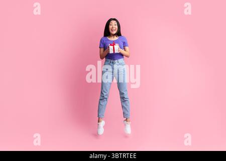 Springen aufgeregt asiatische Dame halten und geben Geschenk-Box Stockfoto