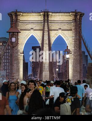 Brooklyn Bridge Fußgänger, die bei Sonnenuntergang am Abend und in der Nacht spazieren gehen, sehen Sie die Kabel und Steinbögen in Lower Manhattan, New York City Stockfoto