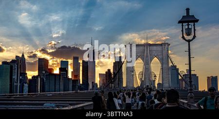 Brooklyn Bridge Fußgänger, die bei Sonnenuntergang am Abend und in der Nacht spazieren gehen, sehen Sie die Kabel und Steinbögen in Lower Manhattan, New York City Stockfoto