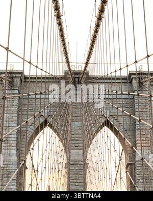Details der Rooklyn Bridge bei Sonnenuntergang und Abenddämmerung aus nächster Nähe von Kabeln und Steinbögen in Lower Manhattan New York City Stockfoto