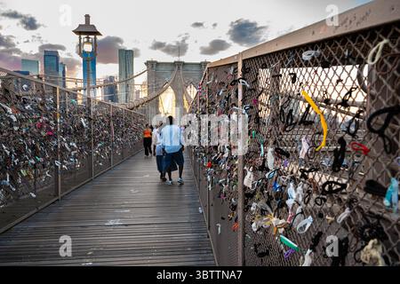 Brooklyn Bridge Fußgänger, die bei Sonnenuntergang am Abend und in der Nacht spazieren gehen, sehen Sie die Kabel und Steinbögen in Lower Manhattan, New York City Stockfoto