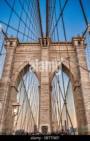 Details der Rooklyn Bridge bei Sonnenuntergang und Abenddämmerung aus nächster Nähe von Kabeln und Steinbögen in Lower Manhattan New York City Stockfoto