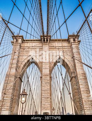 Details der Rooklyn Bridge bei Sonnenuntergang und Abenddämmerung aus nächster Nähe von Kabeln und Steinbögen in Lower Manhattan New York City Stockfoto