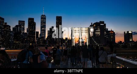 Brooklyn Bridge Fußgänger, die bei Sonnenuntergang am Abend und in der Nacht spazieren gehen, sehen Sie die Kabel und Steinbögen in Lower Manhattan, New York City Stockfoto
