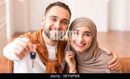 Fröhliche Muslimische Junge Familie Zeigt Den Schlüssel Des Neuen Hauses Im Haus Stockfoto