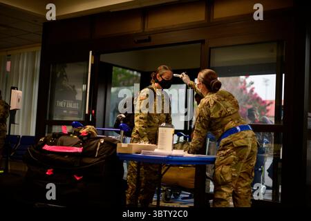 12. August 2020 - Travis Air Force Base, Kalifornien, USA - US Air Force Airman Sarah Cramer, 60th Aerial Port Squadron Passagierterminal Agent, rechts, nimmt die Temperatur von Master Sgt. Christina Ford, 436th Logistics Readiness Squadron Flottenmanager von Dover Air Force Base, Delaware, am Passagierterminal auf der Travis Air Force Base, Kalifornien, 12. August 2020. Ford, zusammen mit anderen Airmen, die im Ausland eingesetzt werden. Die Gruppe schloss eine 14-tägige Bewegungsbeschränkung bei Travis AFB ab, um sicherzustellen, dass sie vor dem Einsatz frei von COVID-19 waren. Travis AFB ist einer von 14 kontinentalen US-amerikanischen Bundesstaaten Stockfoto
